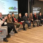 Intervenants d'un colloques assis sur des chaises sur une scène